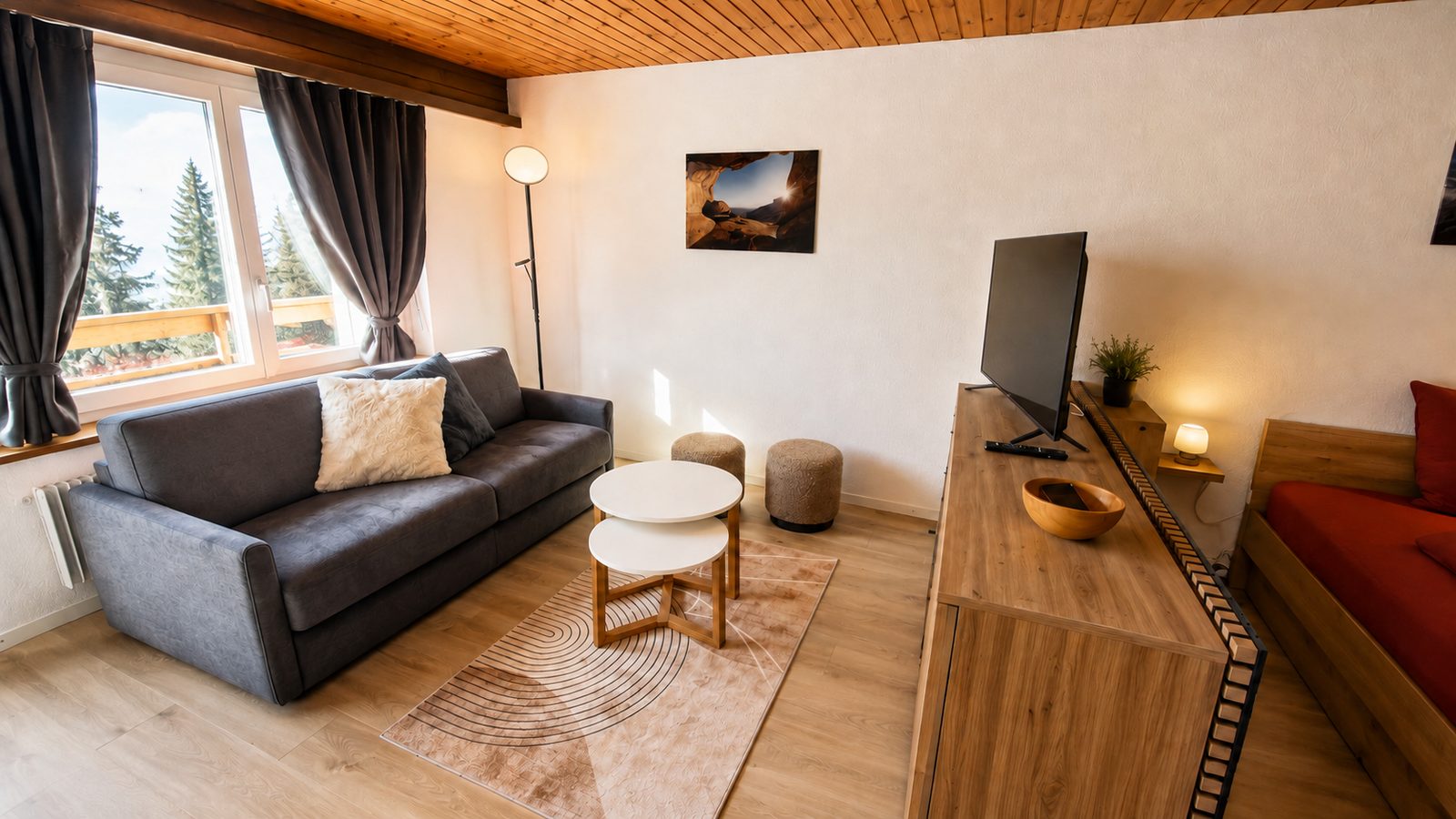 Salon du studio à Loèche-les-Bains : canapé, télévision et fenêtre sur le balcon