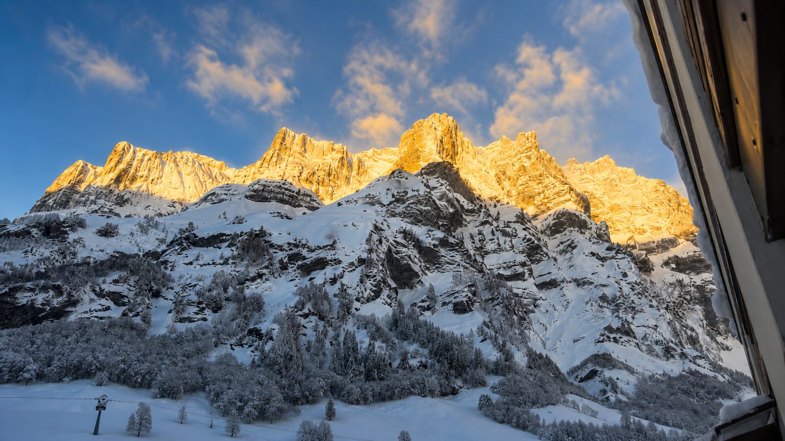Vue depuis le balcon du studio : parois enneigées de Loèche-les-Bains au soleil levant
